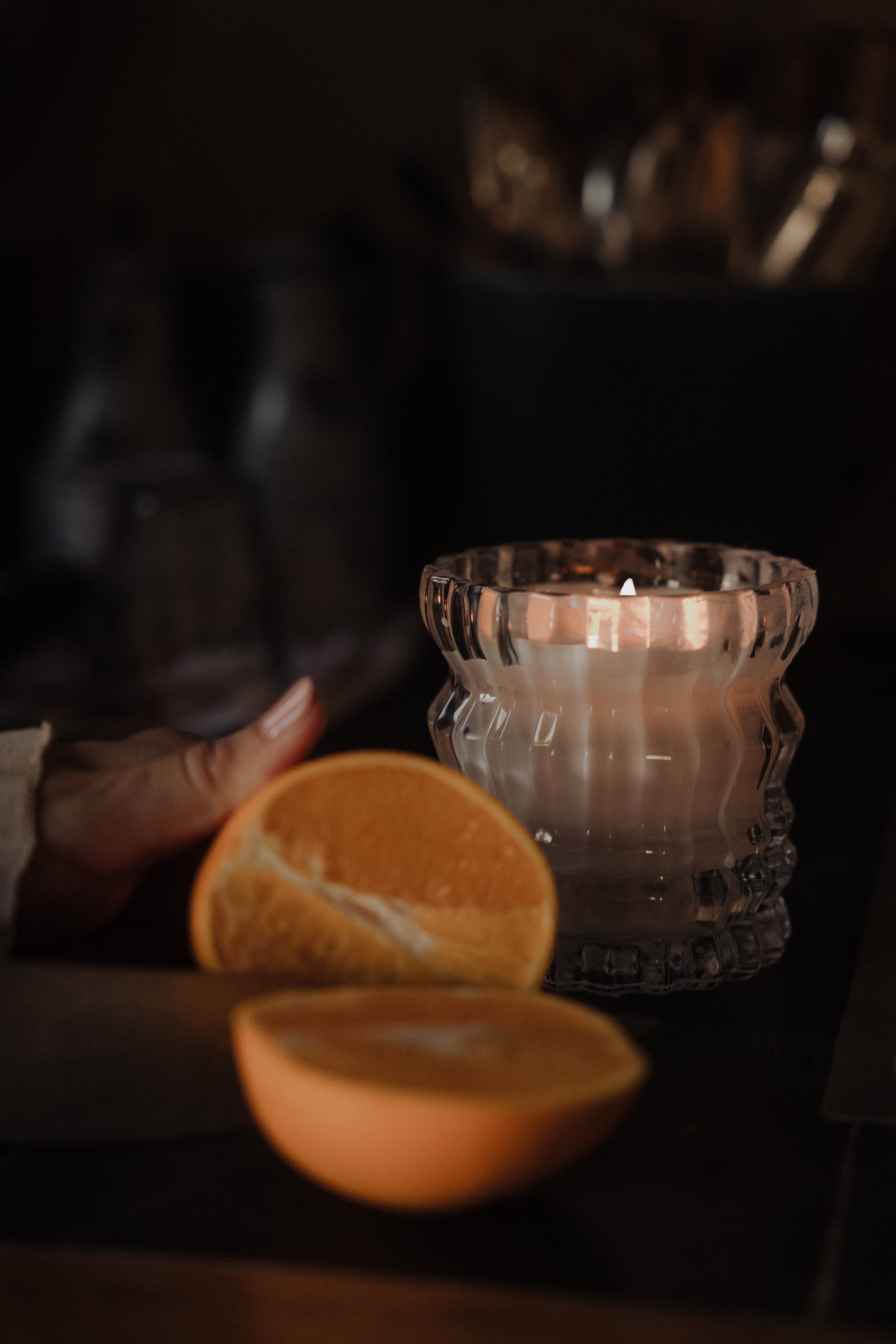 The Arlow candle glows softly in the background, with sliced bergamots placed in front, echoing the candle's signature keynote.