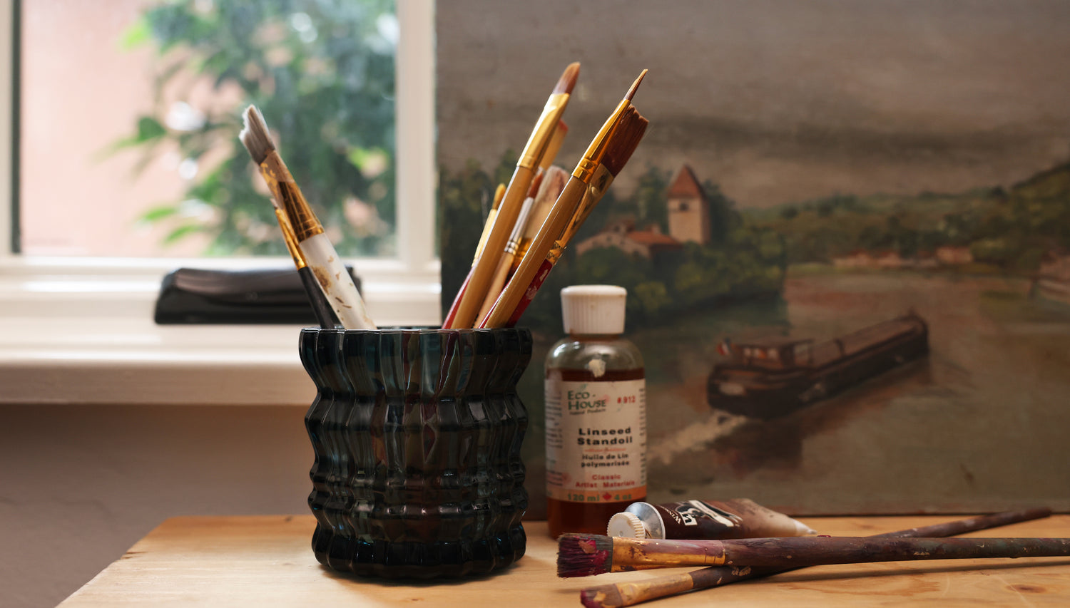 The Noel candle shown being repurposed by now holding a collection of paintbrushes.