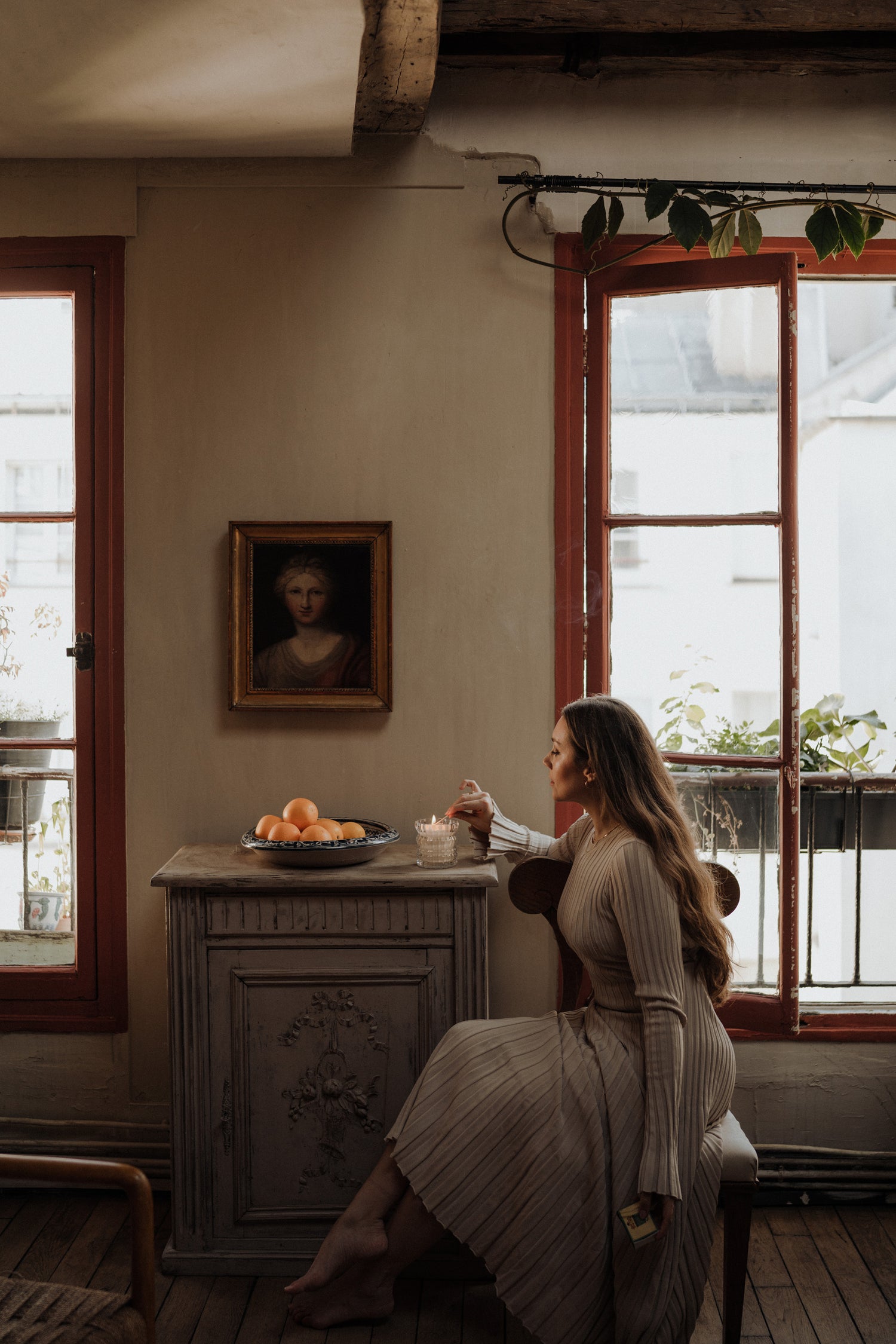 MaCenna Lee sits in a chair at the table, gently lighting the Arlow candle.