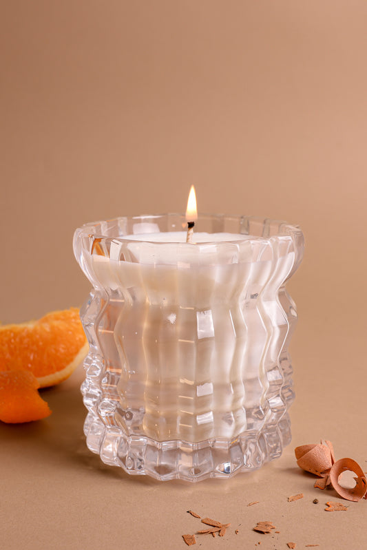 The Arlow Non-Toxic Candle in Textured Glass Vessel from Auden Lueur is displayed with peeled bergamot. 