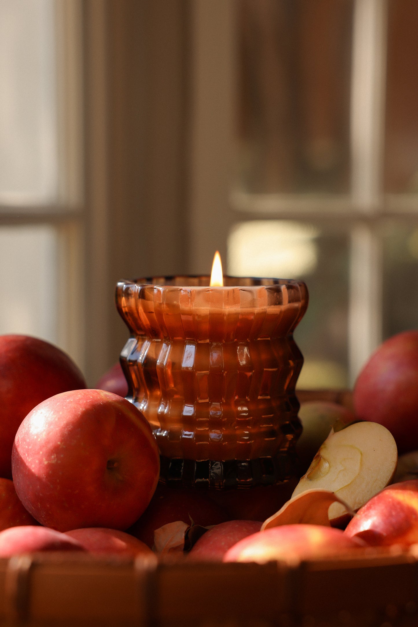 A close-up of the Autumne candle surrounded by apples.