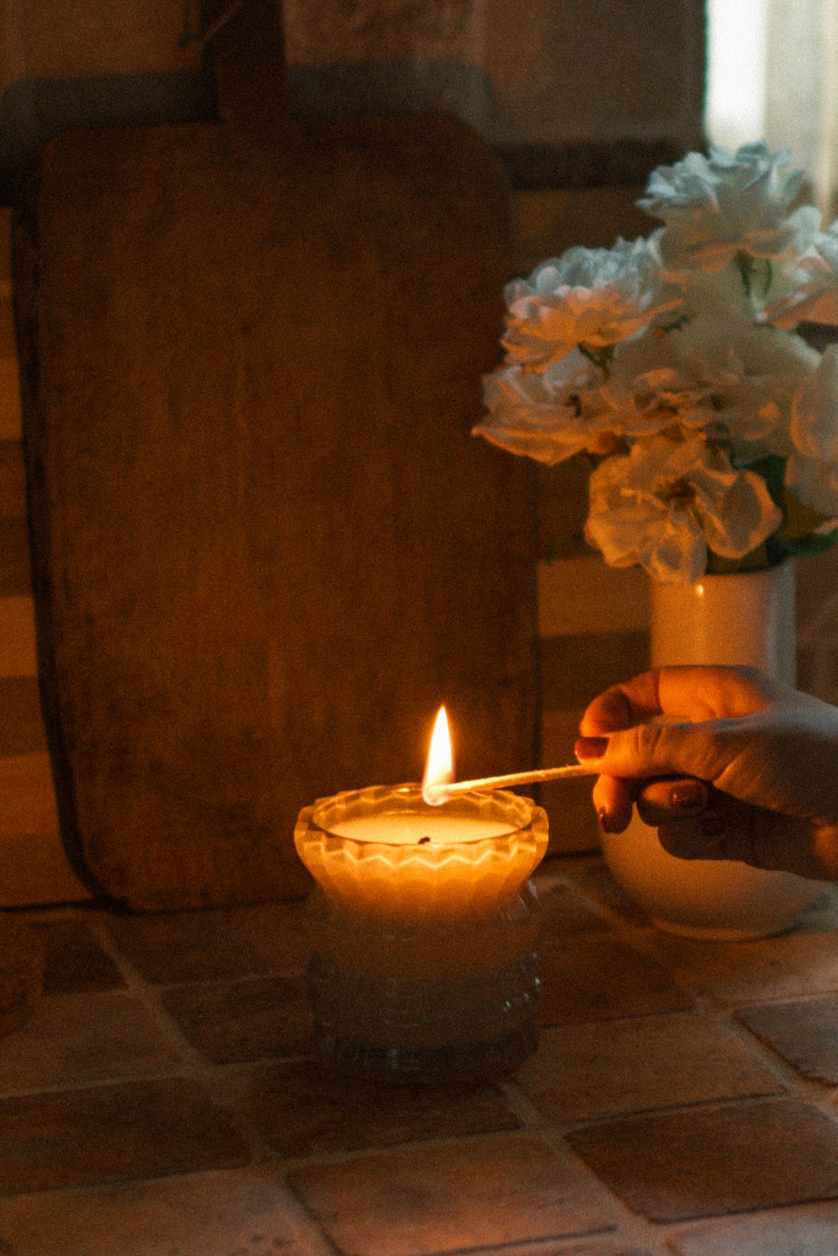 A hand lights the Ellori Non-Toxic Candle in Textured Glass Vessel.