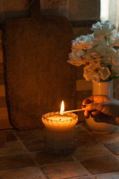 A hand lights the Ellori Non-Toxic Candle in Textured Glass Vessel.