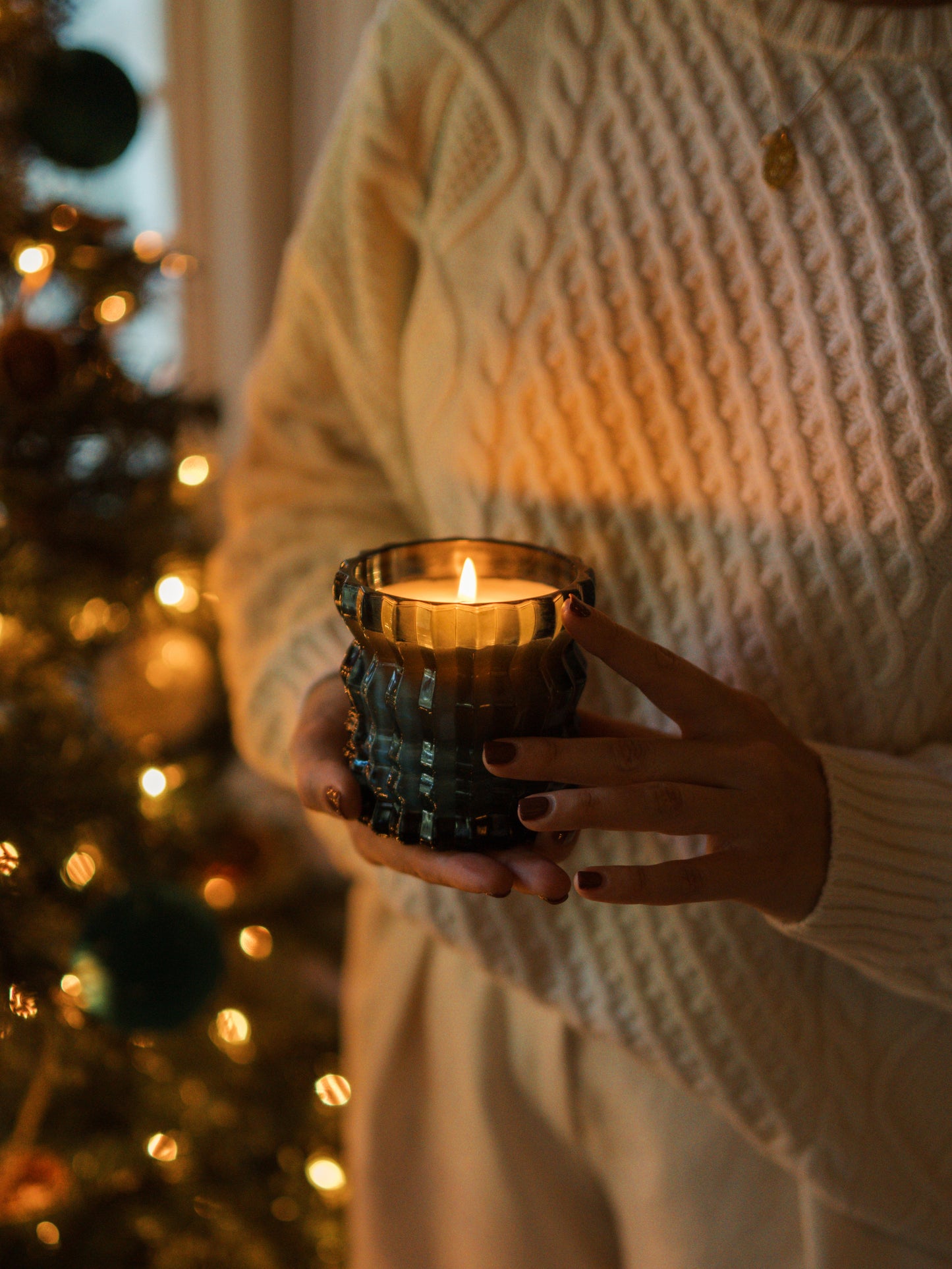 The Noel candle is lit as it is held in the palm of a hand.
