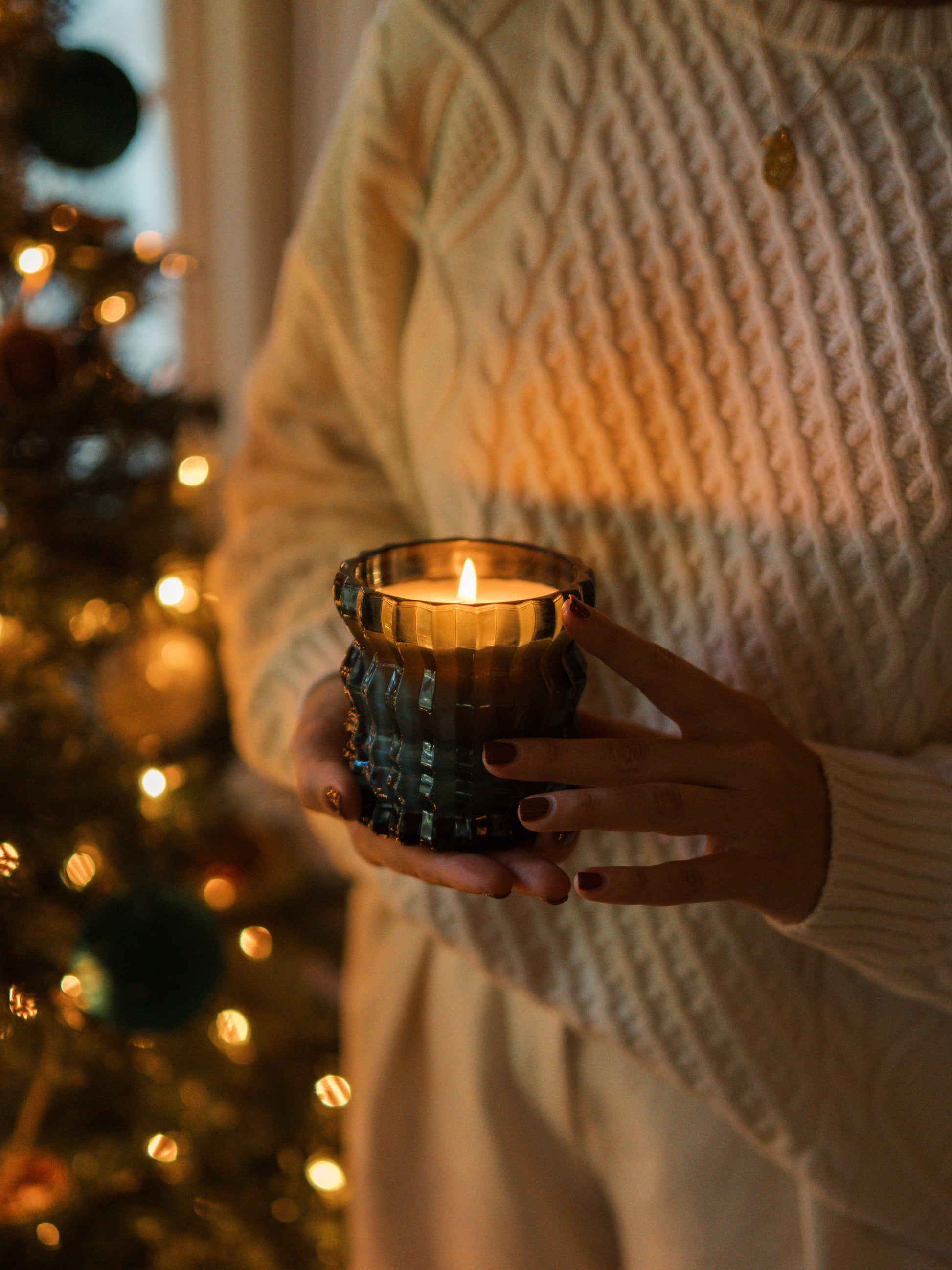 The Noel candle is lit as it is held in the palm of a hand.