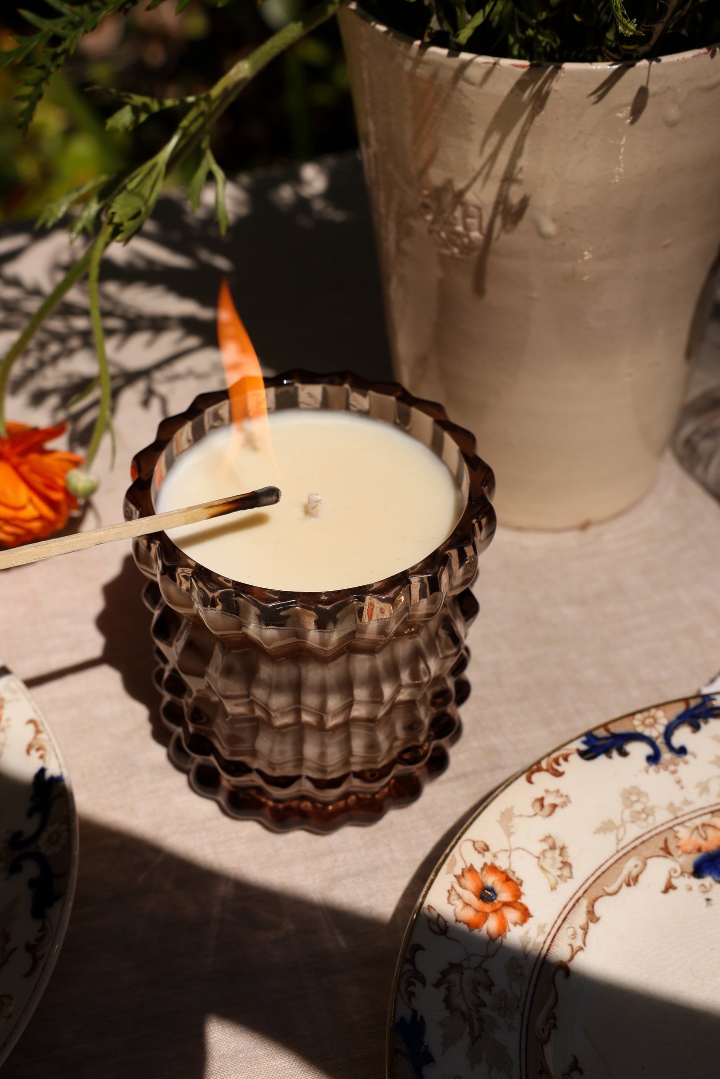 The Willow candle adorns a dinner setting, shown in a close-up as it's being lit.
