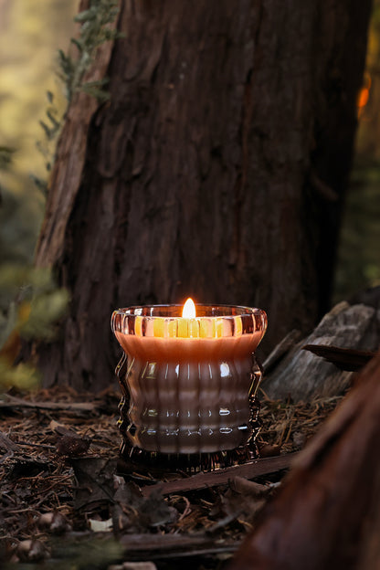 The Willow candle flickers softly in a warm, wooden setting.
