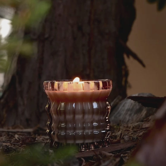 The Willow candle flickers softly in a warm, wooden setting.