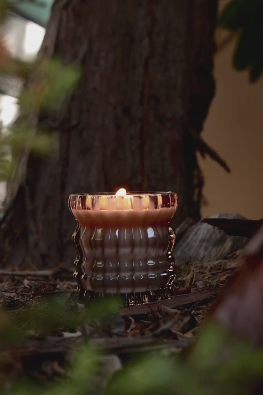 The Willow candle flickers softly in a warm, wooden setting.
